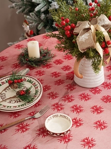 Close-up of red Christmas tablecloth featuring white snowflake patterns and festive texture