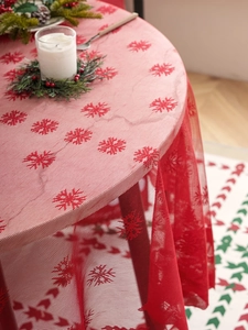 Close-up of red lace Christmas tablecloth with snowflake patterns and holiday decor
