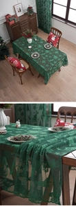 Detailed close-up of dark green lace tablecloth with Christmas tree and elk embroidery