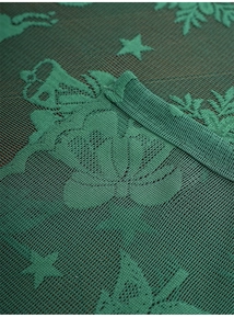 Macro shot of dark green lace Christmas tablecloth with reindeer and snowflake patterns