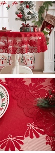Close-up of red Christmas lace tablecloth with hollow patterns of festive bells and flowers