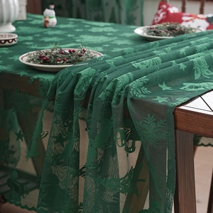 Dark green Christmas lace tablecloth featuring reindeer and snowflakes in a festive home setting