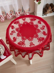 Detail van rood kant rond tafelkleed met witte kerstmotieven zoals de kerstman en bellen
