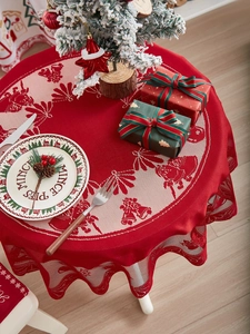 Detail van het rode kerstkant tafelkleed met patronen van kerstklokken en de kerstman