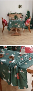 Detailed texture of dark green Christmas tablecloth with festive reindeer and Santa prints