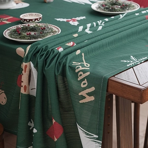 Dark green Christmas tablecloth with reindeer and snowflake prints on a wooden table