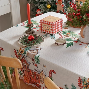 Christmas themed tablecloth featuring snowy cottages and pine branches on textured fabric
