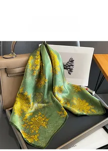 Close-up of olive green silk scarf with yellow floral print on a brown leather bag