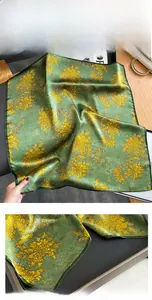 Detail of dark green silk scarf featuring golden chrysanthemum patterns and fine hem edges