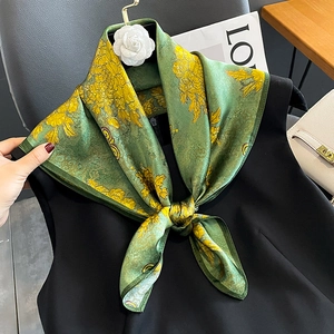 Fashionable silk scarf with green and yellow floral print tied on a black dress