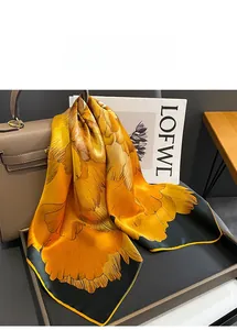 Detail of silk scarf with orange floral pattern draped over a leather handbag