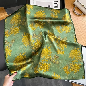 Detailed macro view showing the hand-rolled hem and smooth silk texture of the green scarf