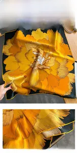 Detail of silk scarf showing vibrant yellow peony floral print on dark green fabric