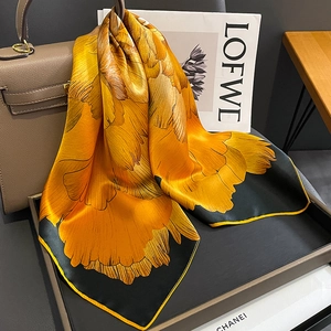 Elegant silk scarf with large orange floral print on black background with yellow trim