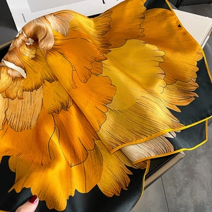 Detail of silk square scarf featuring yellow floral patterns on a black background