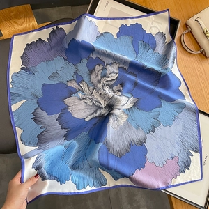 Detail of silk square scarf featuring vibrant purple floral prints and fine rolled edges