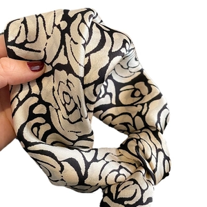 Elegant champagne silk scarf featuring black camellia print with smooth satin luster finish