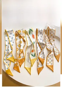 Close-up of long silk scarves with floral and geometric prints for handbag styling