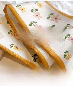 Close-up of double-layered floral satin scarf with orange borders and smooth texture