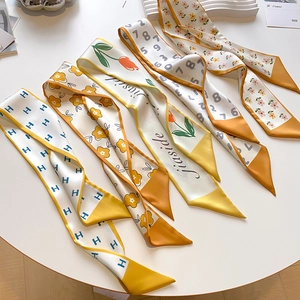 Flat lay of multiple double-sided printed silk twilly scarves on a white table