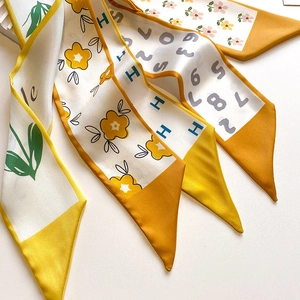 Detail of silk skinny scarves showing four vibrant floral and geometric prints for handbags