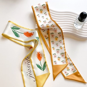 Detail of long silk scarf with orange tulip print on wavy display stand with decor