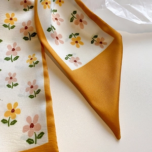 Close-up of mustard yellow floral skinny silk scarf with delicate twill fabric texture