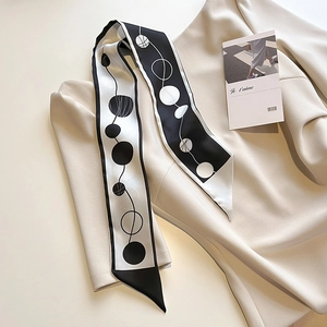 Détail d'un élégant foulard twilly noir et blanc à motifs géométriques sur un tricot