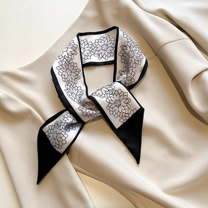 Gros plan d'un foulard twilly noir et blanc à motif floral noué comme une cravate chic