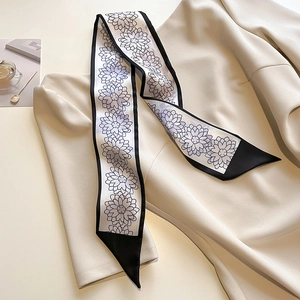 Détail d'un foulard twilly noir et blanc à fleurs sur un chemisier en mousseline