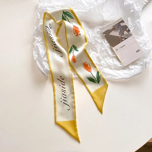 Close-up of a floral skinny silk scarf with orange tulips on a textured background
