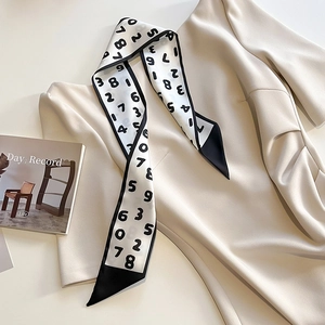Détail d'un foulard étroit de style français avec chiffres noirs sur une robe beige