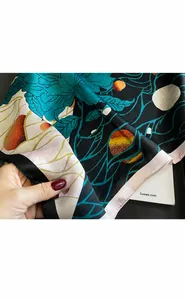 Macro shot of silk scarf showing refined edge stitching and colorful botanical leaf prints