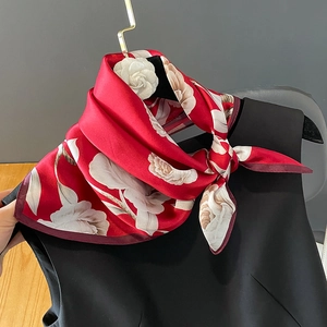 Detailed view of red silk square scarf with white floral pattern on a black dress