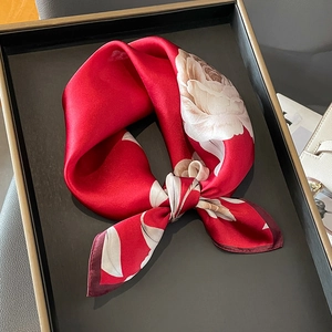 Close-up of silk square scarf in deep red with white floral patterns and rolled edges
