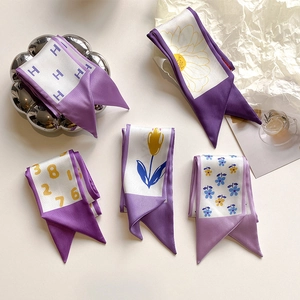 Dettaglio di foulard in seta viola con stampe a margherita e lettere su raso lucido