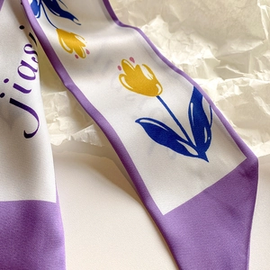 Vista macro di foulard Twilly a fiori con bordi viola e consistenza satinata
