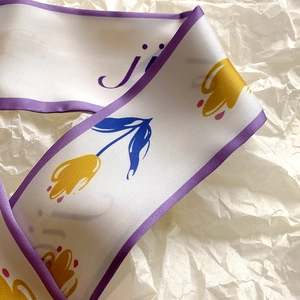 Dettaglio di un foulard di seta bianco con bordo viola e motivi floreali di tulipani