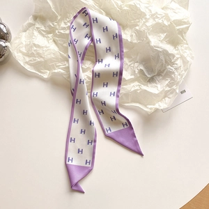 Dettaglio macro della sciarpa twilly in seta con motivo H viola e bordo lilla