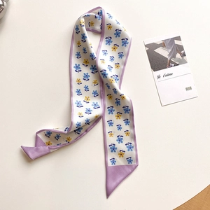Dettaglio della sciarpa twilly con fiori blu e gialli su seta bianca lucida