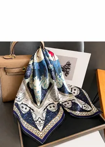 Close-up of lightweight paisley silk scarf tied on handbag for elegant styling