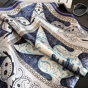 Detail of silk scarf with navy paisley pattern and smooth lustrous texture