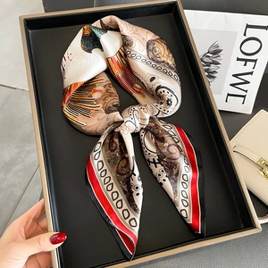 Elegant bohemian silk scarf with paisley print in red and gold on a display tray