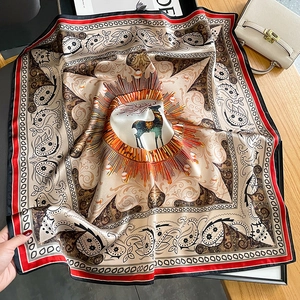 Silk scarf with paisley pattern and elk design displayed on a rustic wooden table