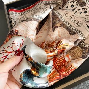 Detail of champagne silk scarf featuring vintage paisley patterns and a smooth texture