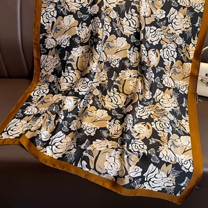 Detail of silk-like scarf featuring rose and butterfly patterns on leather background