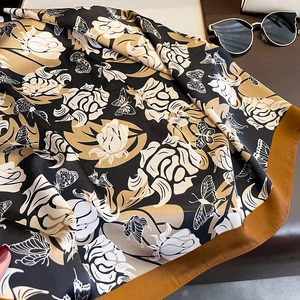 Detailed view of floral print silk scarf featuring roses and butterflies on leather