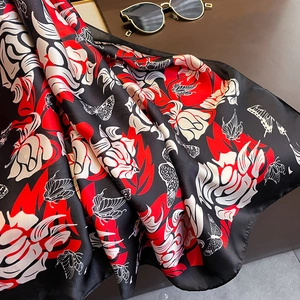 Detail of red and black silk-like scarf with butterfly print and smooth satin texture