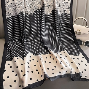 Élégant foulard en soie noir et blanc avec pois et motifs géométriques sur canapé