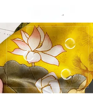 Detailed texture of yellow faux silk scarf featuring elegant pink lotus floral prints